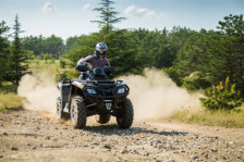 Man riding an ATV coming out of the forest