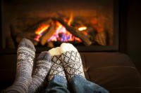 Picture of sock covered feet in front of a warm fire in a fireplace